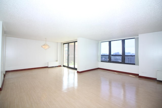 spare room with baseboards, wood finished floors, and a notable chandelier