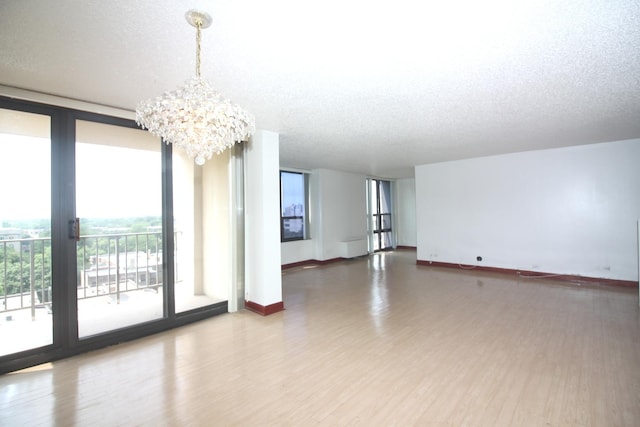 spare room with a textured ceiling, a wall of windows, and wood finished floors