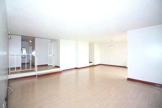 empty room featuring a textured ceiling, baseboards, and wood finished floors