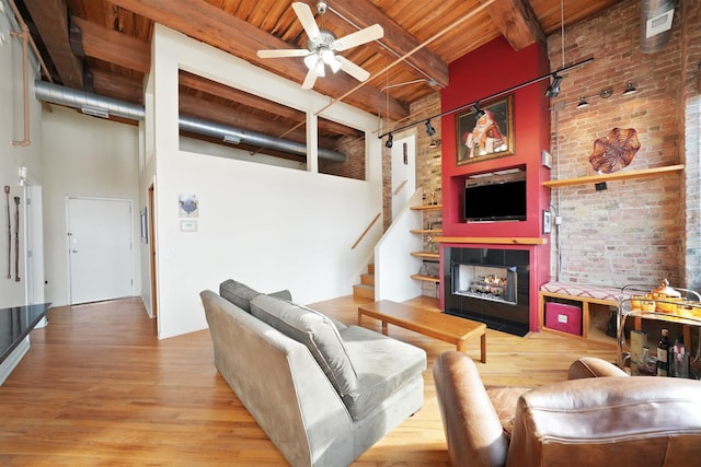 living room featuring light wood-type flooring, wooden ceiling, a high ceiling, and beamed ceiling