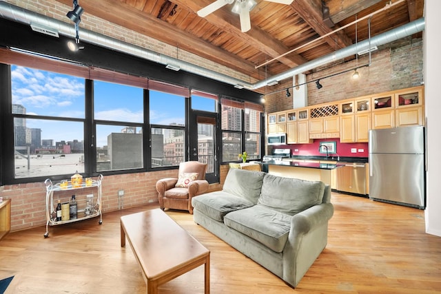 living area featuring a view of city, a high ceiling, light wood-style flooring, and brick wall