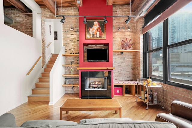 living area featuring brick wall, a lit fireplace, and wood finished floors