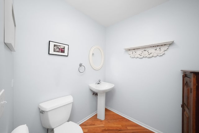 bathroom with a sink, wood finished floors, toilet, and baseboards