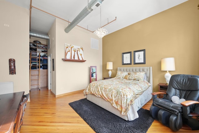 bedroom featuring a chandelier, wood finished floors, visible vents, and baseboards