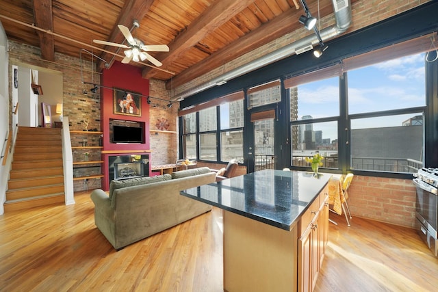 kitchen featuring dark countertops, brick wall, open floor plan, light wood-style floors, and a fireplace