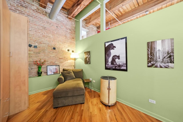 living area with beam ceiling, wooden ceiling, baseboards, and wood finished floors