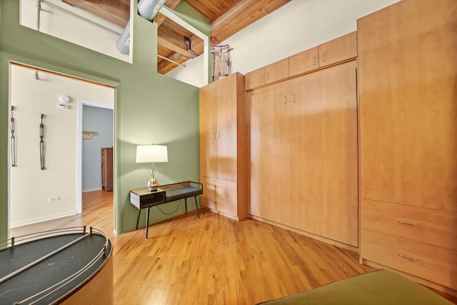 bedroom featuring beam ceiling and light wood-style flooring