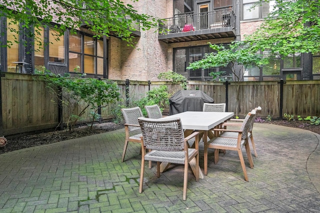 view of patio with outdoor dining area, fence, and grilling area