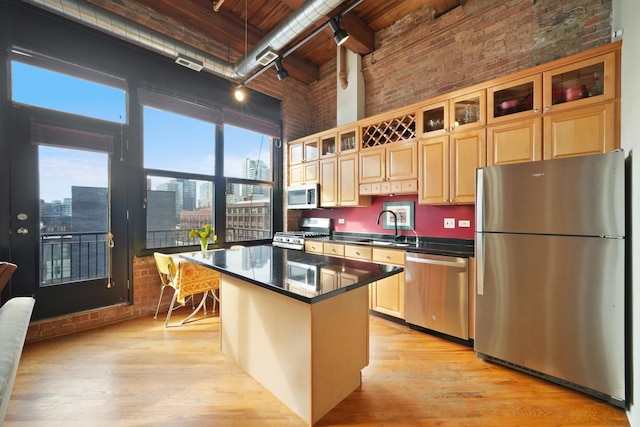 kitchen with dark countertops, a kitchen island, stainless steel appliances, a city view, and a sink