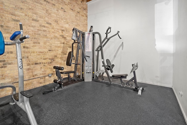 exercise area featuring brick wall and baseboards