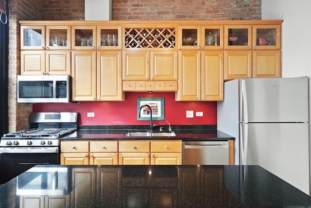 kitchen featuring stainless steel appliances, brick wall, glass insert cabinets, and a sink