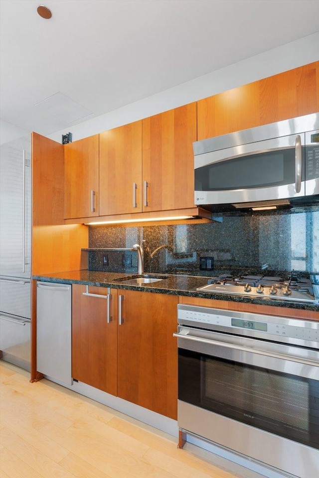 kitchen featuring brown cabinetry, appliances with stainless steel finishes, tasteful backsplash, and a sink