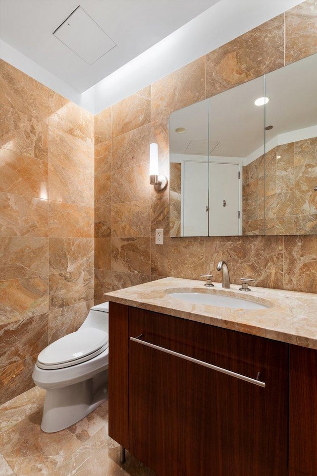 bathroom featuring vanity, tile walls, and toilet