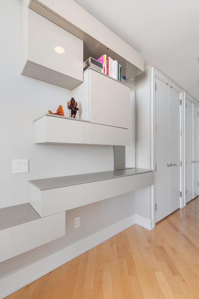 corridor with light wood finished floors and baseboards