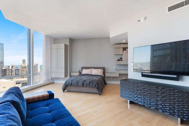 bedroom with visible vents, baseboards, wood finished floors, and expansive windows