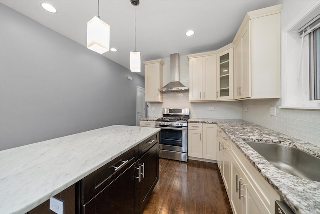 kitchen with stainless steel range with gas stovetop, dark wood finished floors, wall chimney range hood, and decorative backsplash