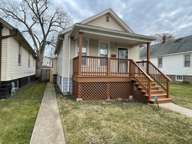 shotgun-style home with a porch and a front lawn