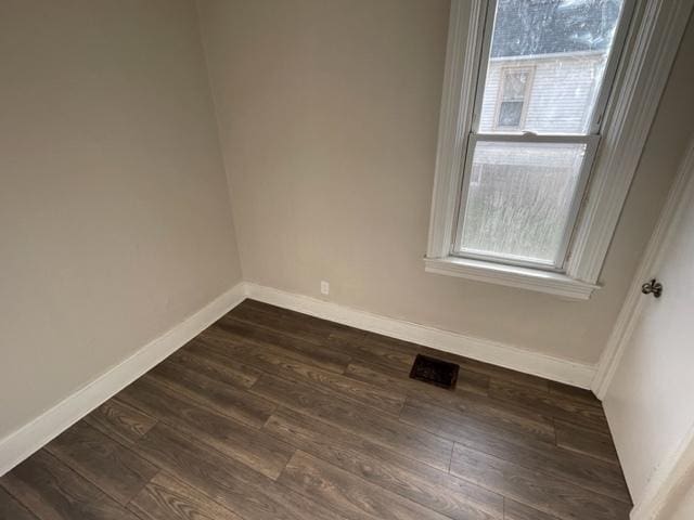 unfurnished room featuring dark wood-type flooring and baseboards