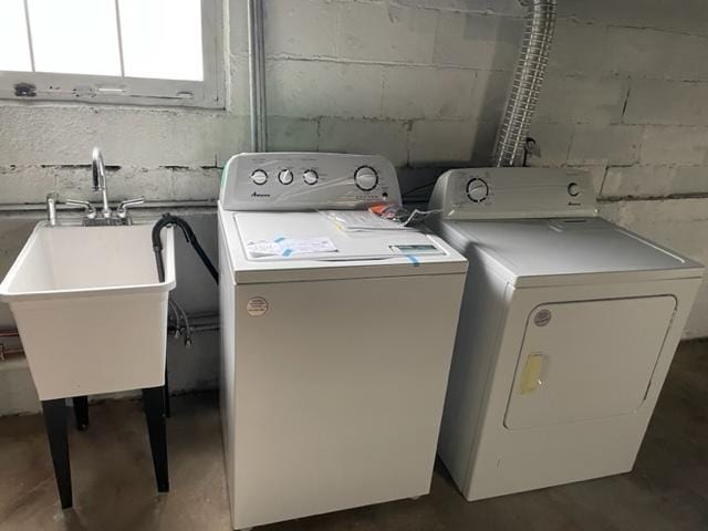 clothes washing area with a sink and separate washer and dryer