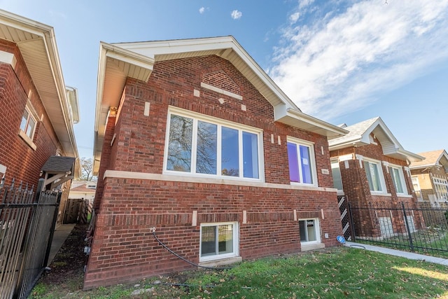 view of side of property with a yard, brick siding, and fence