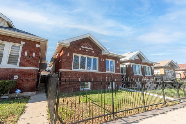 view of front facade with a fenced front yard, a front lawn, and brick siding