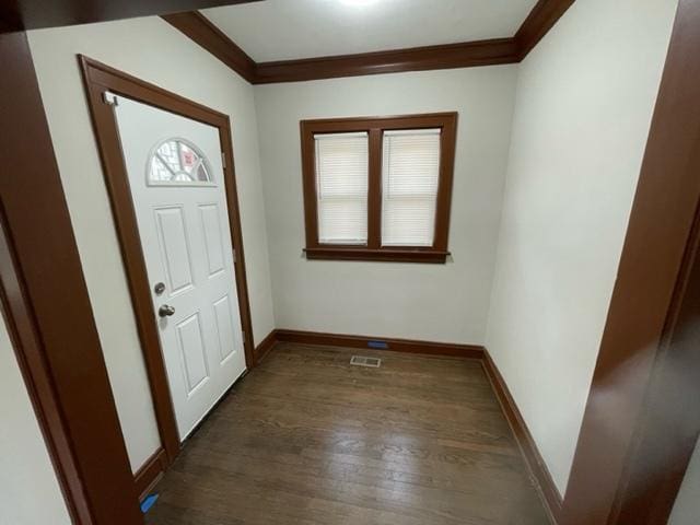 foyer entrance featuring dark wood-style floors, crown molding, and baseboards