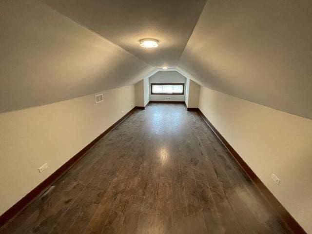 bonus room with lofted ceiling, visible vents, baseboards, and dark wood-type flooring