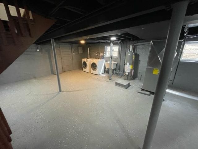 basement featuring separate washer and dryer, gas water heater, and a sink