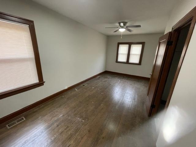 unfurnished room featuring visible vents, ceiling fan, baseboards, and wood finished floors