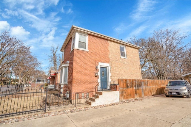 view of home's exterior with a fenced front yard, concrete driveway, and brick siding