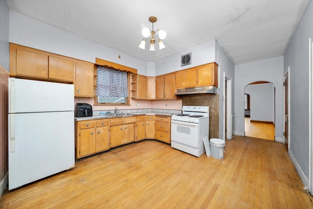 kitchen with white appliances, visible vents, arched walkways, under cabinet range hood, and a sink