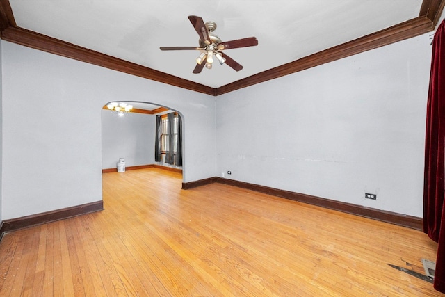 spare room featuring arched walkways, light wood-type flooring, baseboards, and crown molding