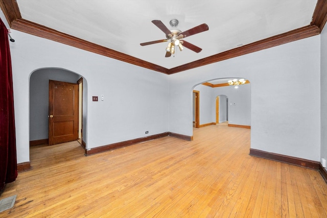 unfurnished room featuring arched walkways, visible vents, light wood-style flooring, and baseboards