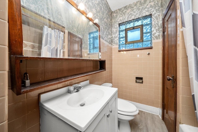 full bath featuring tile walls, vanity, toilet, and wallpapered walls