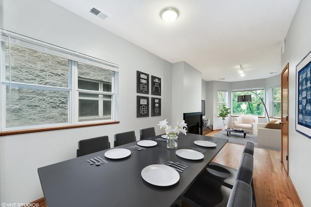 dining room featuring light wood-type flooring, a fireplace, and visible vents