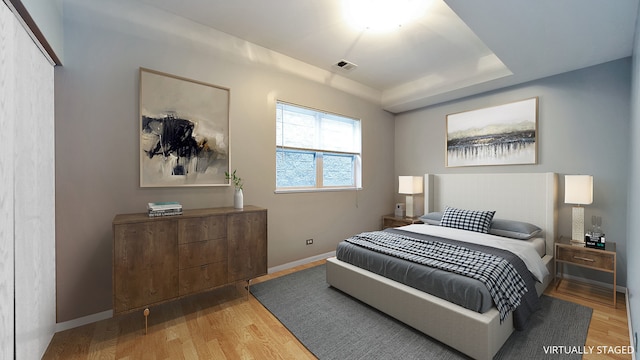 bedroom with visible vents, baseboards, and wood finished floors