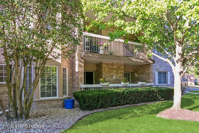 view of front of property featuring a balcony and a front lawn