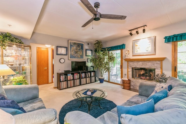 carpeted living area featuring a ceiling fan, a fireplace, a wealth of natural light, and track lighting