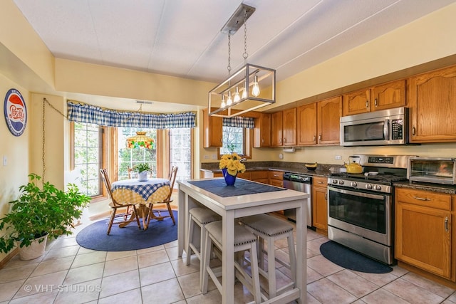 kitchen with appliances with stainless steel finishes, dark countertops, a toaster, and brown cabinets