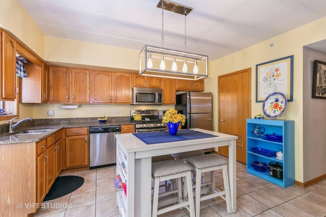 kitchen featuring brown cabinets, a breakfast bar area, appliances with stainless steel finishes, light tile patterned flooring, and a sink