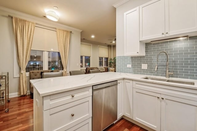 kitchen featuring decorative backsplash, stainless steel dishwasher, white cabinets, a sink, and a peninsula