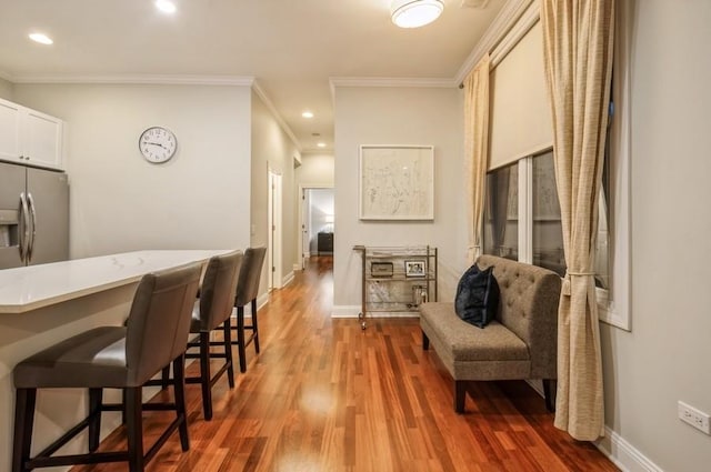 interior space with baseboards, a breakfast bar area, wood finished floors, and stainless steel fridge with ice dispenser