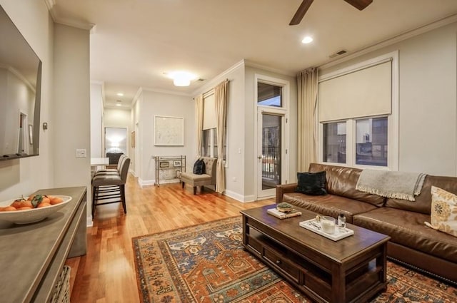 living room with ornamental molding, wood finished floors, visible vents, and baseboards