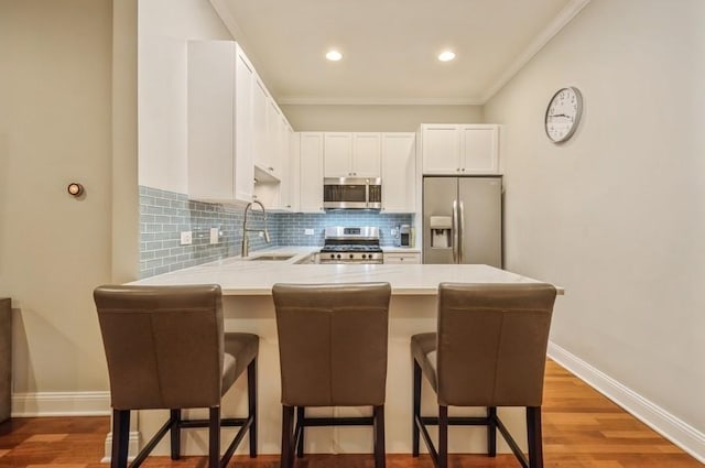 kitchen with decorative backsplash, a peninsula, stainless steel appliances, light countertops, and a sink