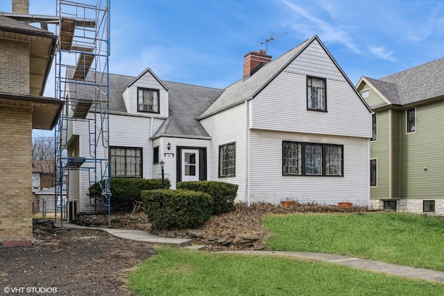 view of front of house with a shingled roof and a front lawn