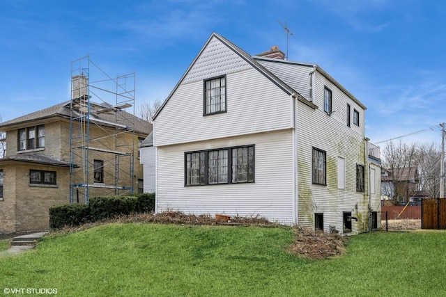 rear view of property featuring a trampoline, a lawn, a chimney, and fence