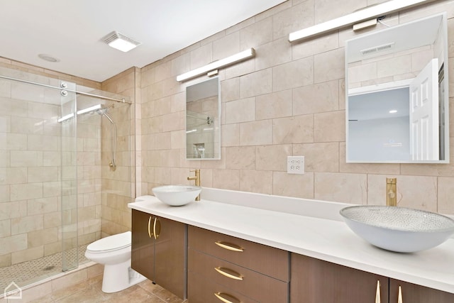 bathroom with a stall shower, tile walls, and a sink