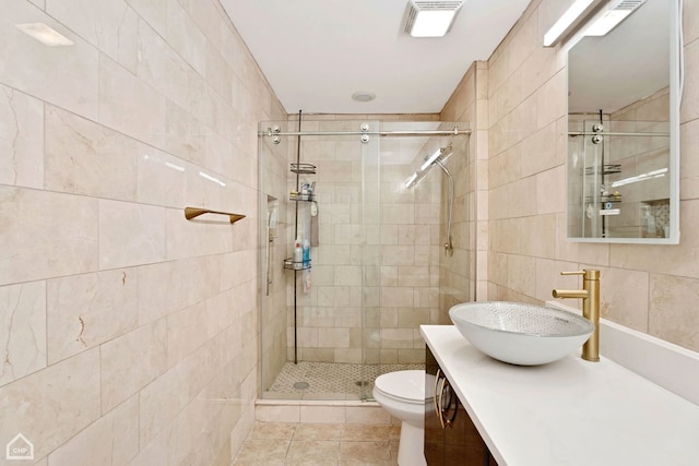 full bath featuring tile patterned flooring, visible vents, vanity, a stall shower, and tile walls