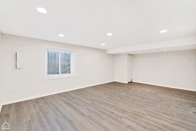 below grade area featuring recessed lighting, baseboards, electric panel, and wood finished floors