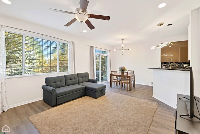 living room featuring recessed lighting, baseboards, wood finished floors, and ceiling fan with notable chandelier